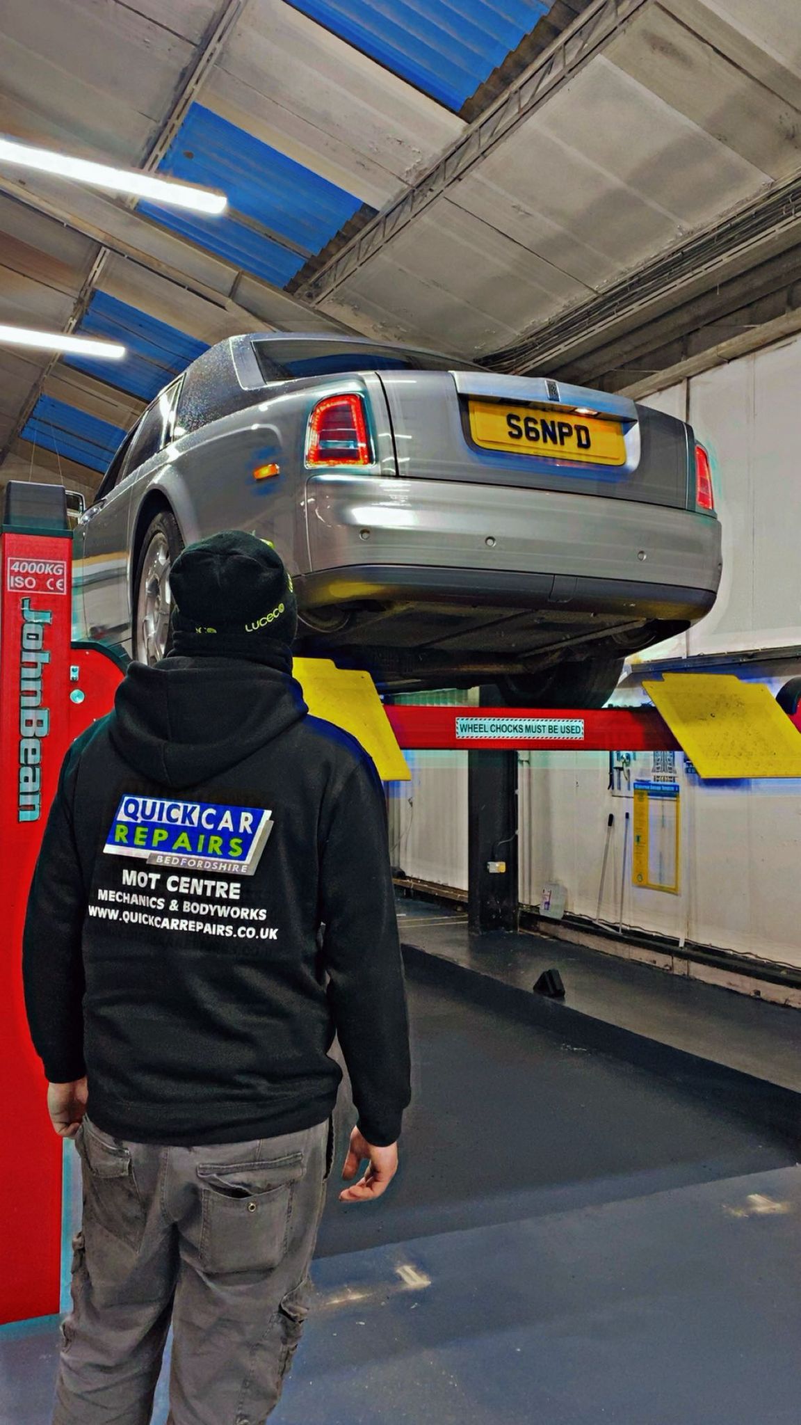 Person photographing scratched rear panel of a silver car using a smartphone for an online repair quote with Quick Car Repairs in Leighton Buzzard